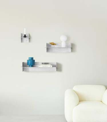 Transparente Normann Copenhagen væghylder med dekorative accessories i et minimalistisk opholdsrum.