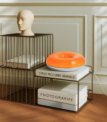 Moderne Lindby bordlampe i levende orange på et dekorativt reolsystem.
