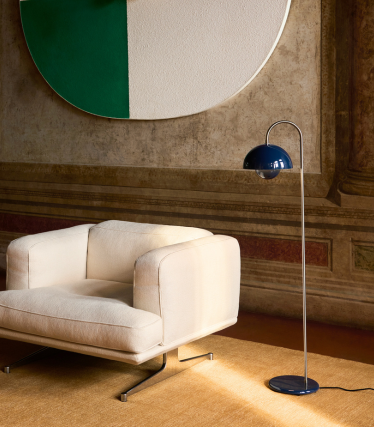En elegant &Tradition-gulvlampe ved siden af en moderne lænestol i et hyggeligt interiør.