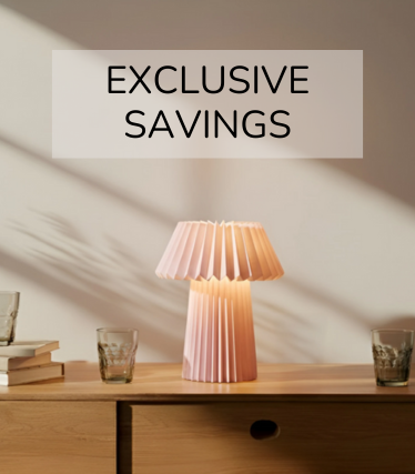 Lyserød bordlampe på en træskænk, omgivet af glas og bøger i det varme sollys.