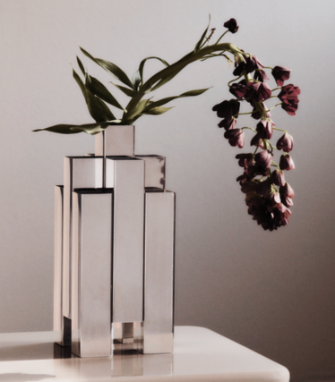 Skulpturel vase i poleret rustfrit stål fra Ferm Living med mørkerøde blomster
