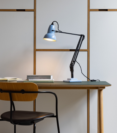 Lyseblå Anglepoise skrivebordslampe på et træbord med en stol