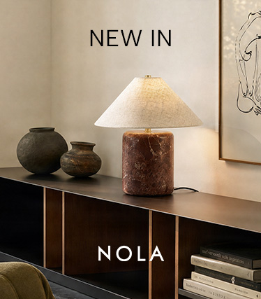 Nola-bordlampe med rødbrun marmorfod og konisk skærm i hør på en mørk skænk. Tekst: „Nyhed – Nola“.