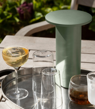 Salviegrønt cylindrisk sidebord/køler på en bakke med glas og drikkevarer udendørs.